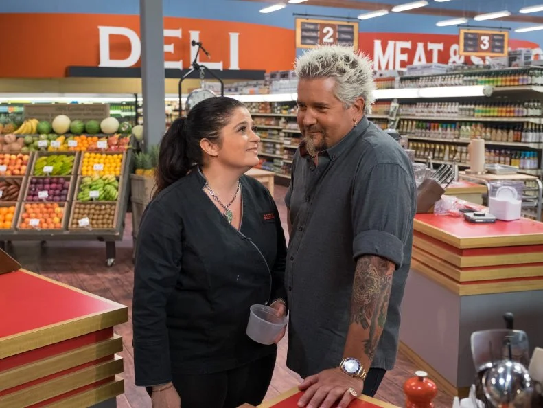 Contestant Alex Guarnaschelli stares at host Guy Fieri, as seen on Food Network's Guy's Grocery Games, Season 10.