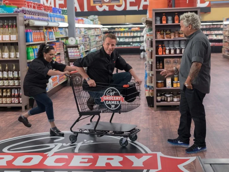 Contestants Maneet Chauhan and Marc Murphy having fun with host Guy Fieri on set, as seen on Food Network's Guy's Grocery Games, Season 10.