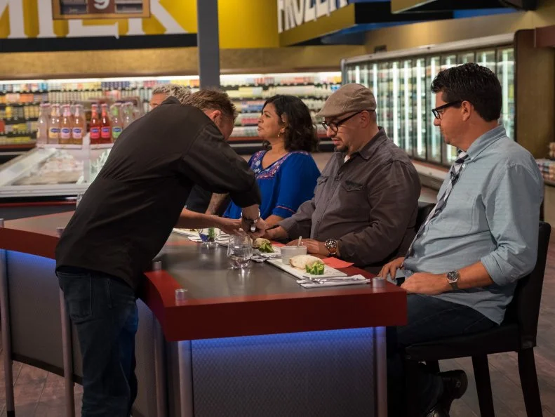 Host Guy Fieri looks on as contestant Marc Murphy provides table service for judges Aarti Sequeira, Carl Ruiz and Troy Johnson, as seen on Food Network's Guy's Grocery Games, Season 10.