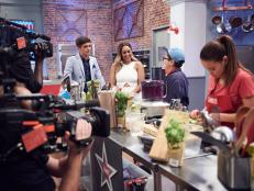 Hosts Donal Skehan and Tia Mowry watch Contestant Liam Waldman preparing his dish, Pomegranate Lemon Calamari with Garbanzo Beans, Fried Eggplant and Red Cabbage Salad, for the Star Challenge, as seen on Food Network Star Kids, Season 1.