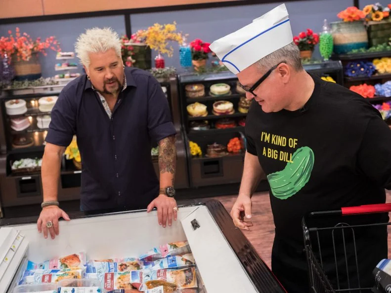 Host Guy Fieri talks to contestant Zane Caplansky as he shops for groceries during the NYC Frozen Food Feud, as seen on Food Network's Guy's Grocery Games, Season 12.