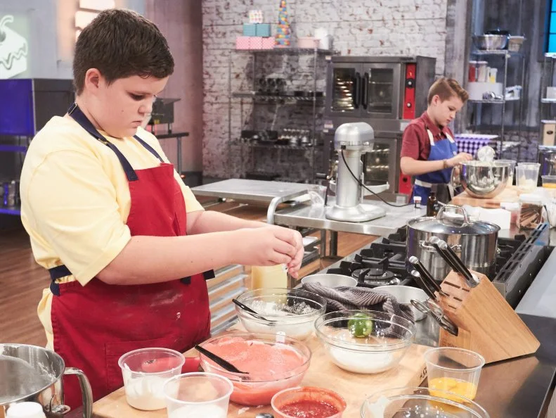 Contestant Aidan Berry preparing his Main Heat dish, Strawberry/Orange/Lemon/Lime Tie Dye Cake with Vanilla Buttercream and White Chocolate Ganache Drizzle and Raspberry and Passionfruit Swirl Ice Cream, as seen on Food Network's Kids Baking Championship, Season 3.