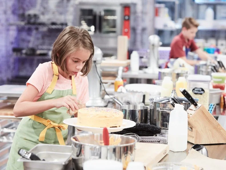 Contestant Audra Tow preparing her Main Heat dish, Orange Flavor Tie Dye Cake with Orange Buttercream and Vanilla with Raspberry Swirl Ice Cream, as seen on Food Network's Kids Baking Championship, Season 3.