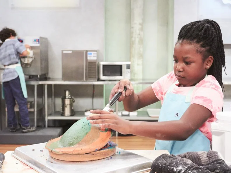 Contestant Kaniyah Cary preparing her Main Heat dish, Vanilla Tie Dye Cake with Vanilla Swirl Buttercream and Vanilla Blackberry Swirl Ice Cream, as seen on Food Network's Kids Baking Championship, Season 3.