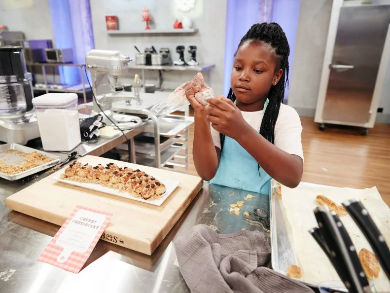Contestant Kaniyah Cary preparing her Main Heat Dish, Éclair with Cherry Cream Cheese Filling topped with Graham Crackers and Raisins, as seen on Food Network's Kids Baking Championship, Season 3.