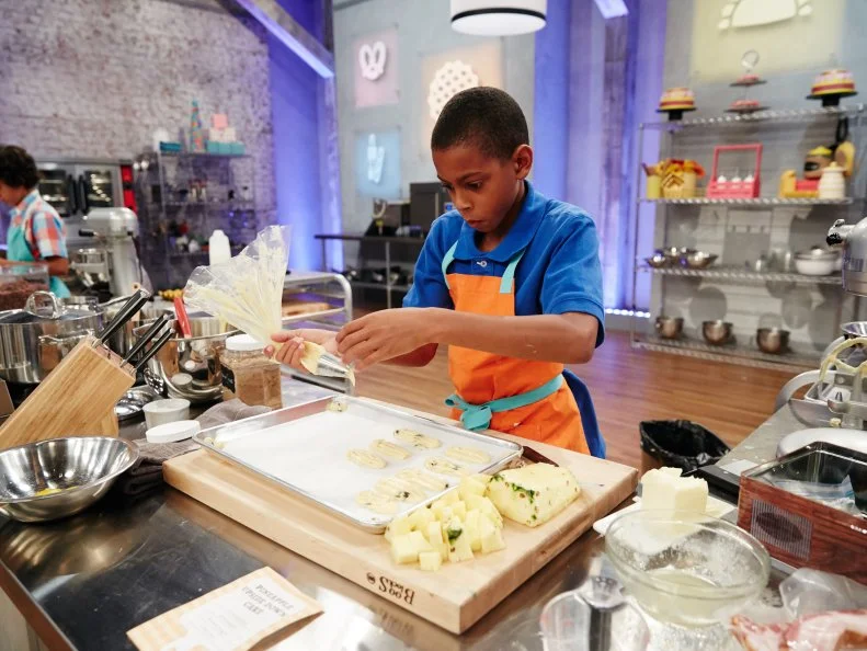 Contestant Reese Smith preparing his Main Heat dish, Raisin Éclair with Cherry, Pineapple and Brown Sugar Pastry Cream, as seen on Food Network's Kids Baking Championship, Season 3.