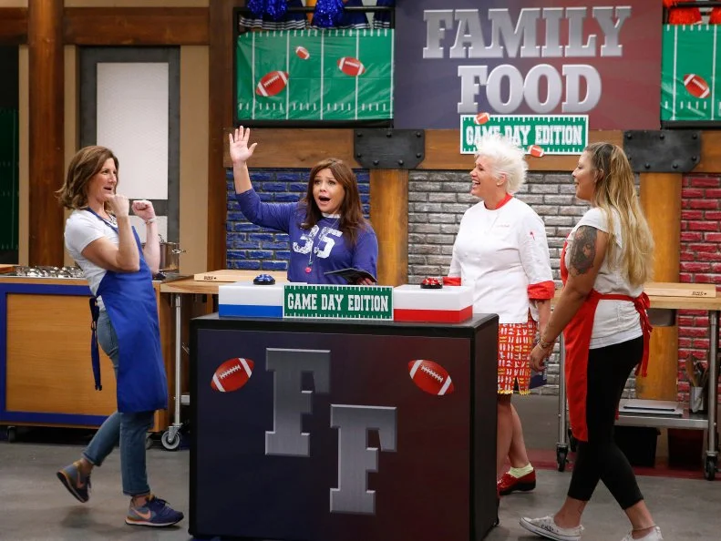 Mentors Rachael Ray and Anne Burrell lead recruits Laura Docker of the blue team and Kayla Kurtz of the red team in a game of Family Food, as seen on Food Network's Worst Cooks in America, Season 10.
