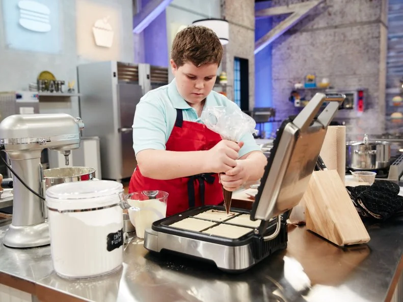 Contestant Aidan Berry preparing his Main Heat dish, Cinnamon Swirl Waffle Cake with Cream Cheese Frosting, Pecans, Cinnamon Crunch Cereal and a Side of Cinnamon Crunch Cereal Ice Cream, as seen on Food Network's Kids Baking Championship, Season 3.
