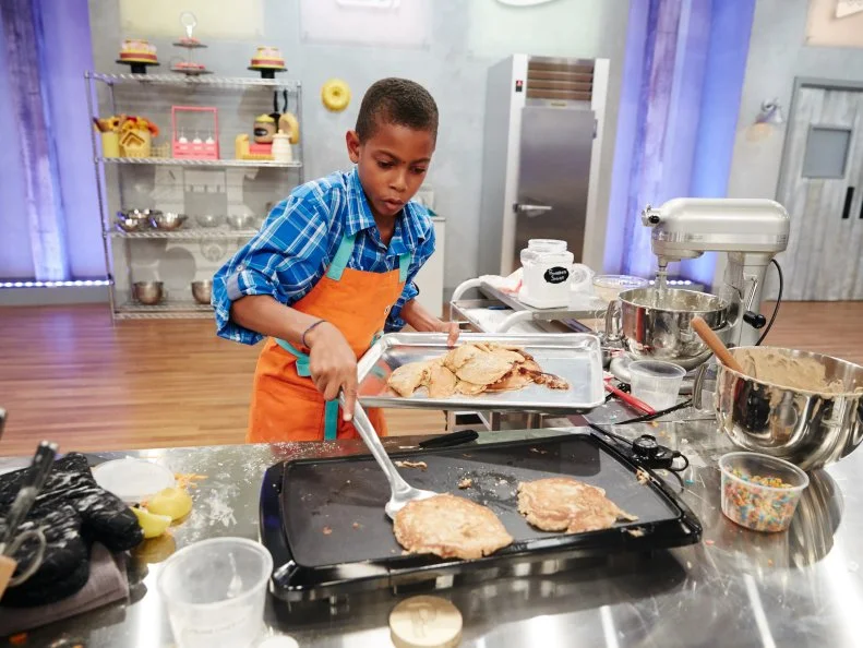 Contestant Reese Smith preparing his Main Heat dish, Carrot Cake Pancake Cake with Cream Cheese Fruit Rice Cereal Buttercream, as seen on Food Network's Kids Baking Championship, Season 3.