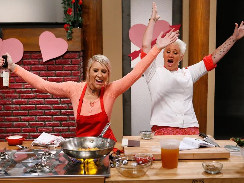 Mentor Anne Burrell celebrates with Mandy Thornton of the red team after guiding her through a flambe as she cooks during the main dish challenge, as seen on Food Network's Worst Cooks in America, Season 10.