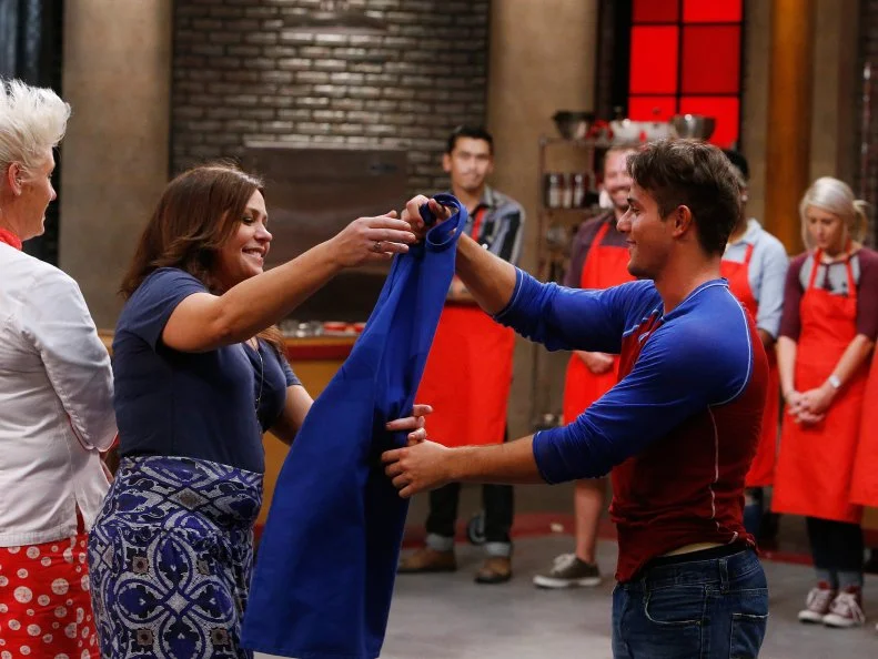 Jake Michaels hands his apron to mentor Rachael Ray after being eliminated from the blue team, as seen on Food Network's Worst Cooks in America, Season 10.