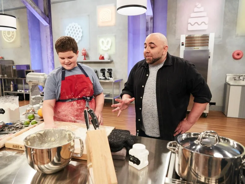 Host Duff Goldman watches contestant Aidan Berry preparing his Main Heat dish, Lime Sugar Cookie with Vanilla Frosting, in the shape of Apps Cheesecake Chess, Pie-Terest, and Fruitcake Ninja, as seen on Food Network's Kids Baking Championship, Season 3.
