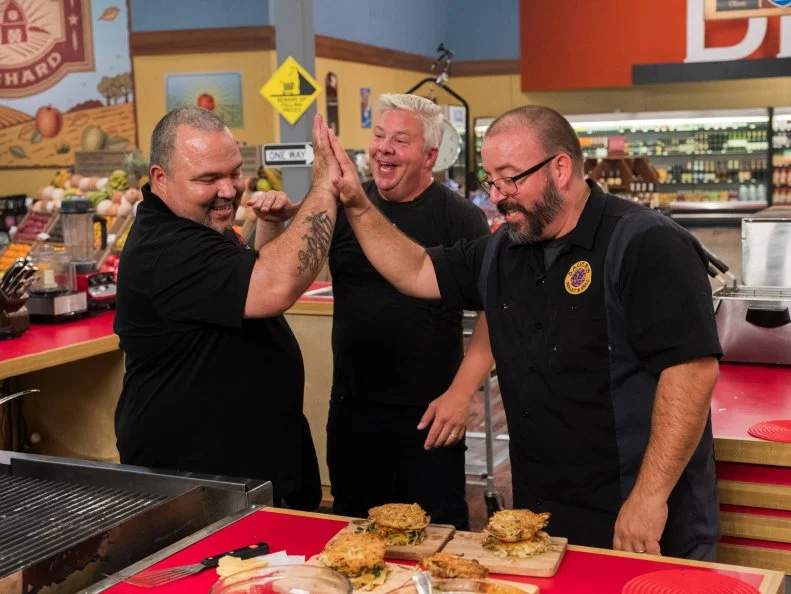 Contestants Adam Sappington, Tye Rhone Bauer and Michell Sanchez celebrate, as seen on Food Network's Guy's Grocery Games, Season 12.