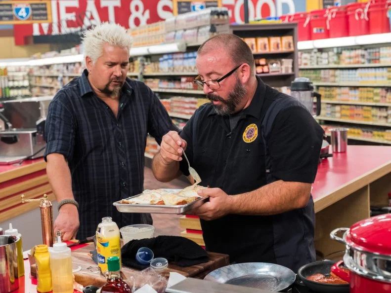 Host Guy Fieri checks in on contestant Tye Rhone Bauer, as seen on Food Network's Guy's Grocery Games, Season 12.