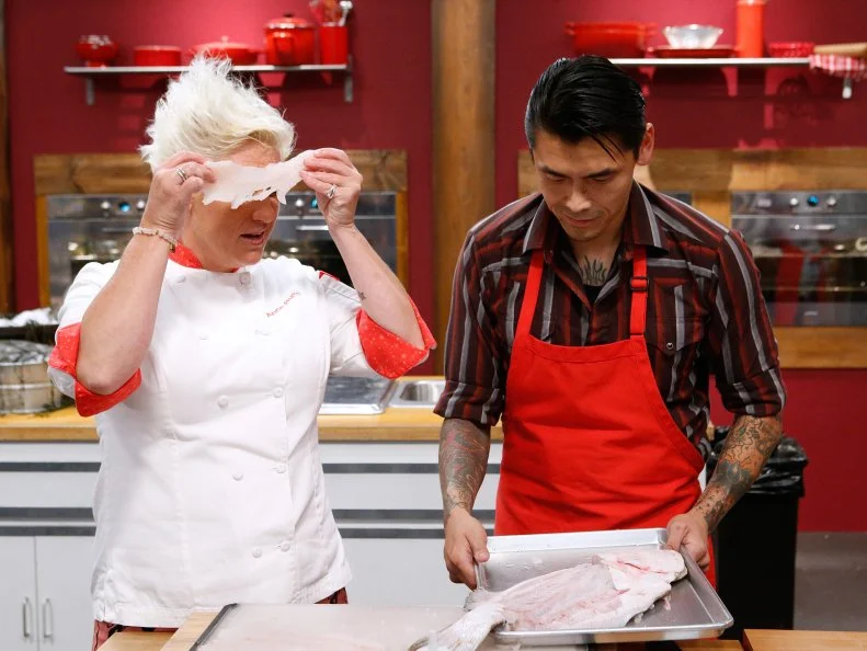 Mentor Anne Burrell checks in on Daniel Mar of the red team as he cooks during the main dish challenge, as seen on Food Network's Worst Cooks in America, Season 10.