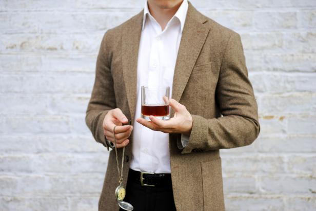 Elegant man holding glass of whiskey