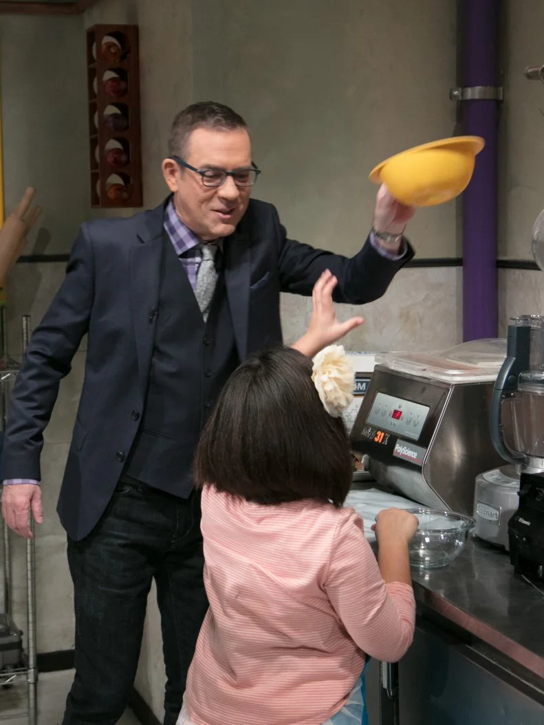 Host Ted Allen helps Junior contestant Olivia Acosta during the appetizer round, as seen on Food Network's Chopped Junior, Season 6.