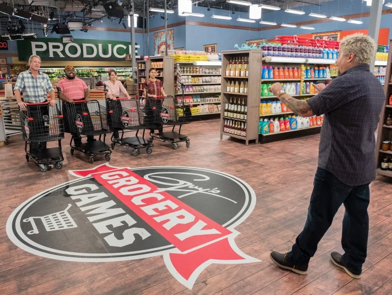 Contestants John Conley, Michael Marina, Kate Newman, and Tracey Shepos wait for Host Guy Fieri to signal the start of the Aisle Down game, as seen on Food Network's Guy's Grocery Games, Season 12.