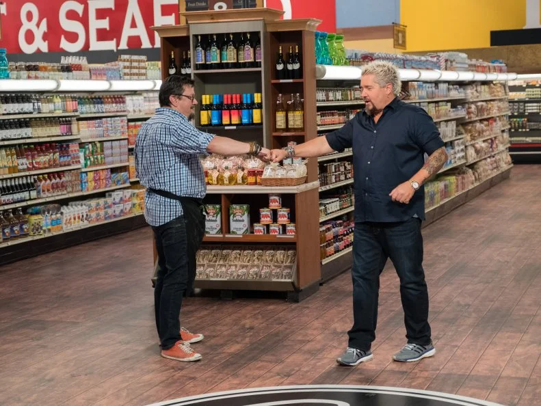 Contestant Tom Ramsey fist bumps Host Guy Fieri, as seen on Food Network's Guy's Grocery Games, Season 12.