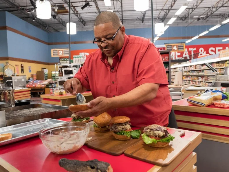 Contestant Glenn "Gator" Thompson spreads sauce on his hamburger buns while plating his dish, as seen on Food Network's Guy's Grocery Games, Season 12.