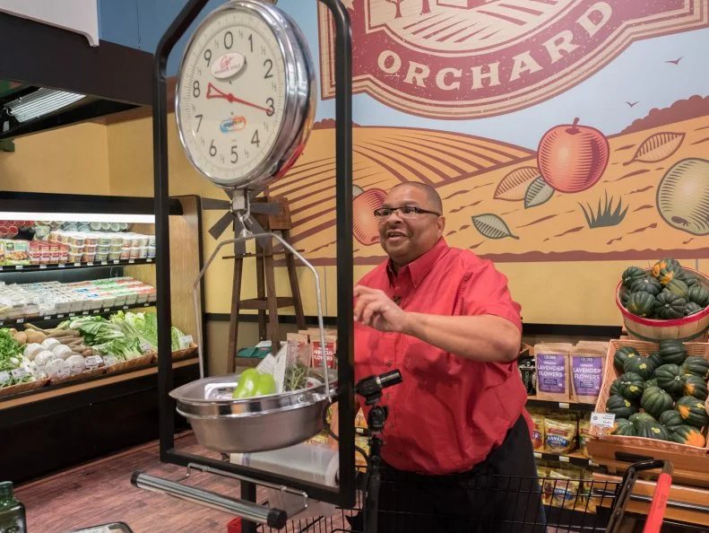 Contestant Glenn "Gator" Thompson checks the scale as he weighs his groceries during the Watch Your Weight Game, as seen on Food Network's Guy's Grocery Games, Season 12.