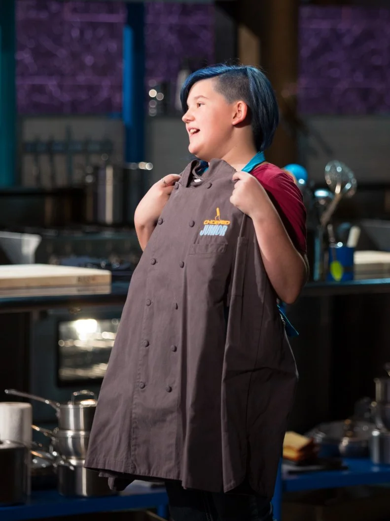 Winning Junior contestant Kenzie Mills reacts to receiving a Chopped Junior Chef's coat during the judging of the dessert round, as seen on Food Network's Chopped Junior, Season 6.