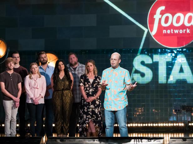 Contestants (left) Trace Barnett, Blake Baldwin, Addie Gundy, Cory Bahr, Suzanne Lossia, Rusty Hamlin and Amy Pottinger (right) behind contestant Jason Smith introducing himself for the Mentor Challenge, Ready, Set...Rehearse!, as seen on Food Network Star, Season 13.