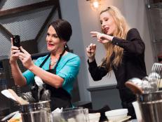 Contestants Joy Thompson and Danushka Lysek having fun recording Instagram stories in the Mentor Challenge Passing the Bar, as seen on Food Network's Comeback Kitchen, Season 2.