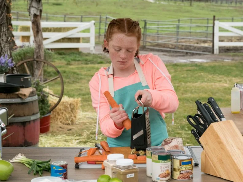 Contestant Hailey Hill shredding a carrot for her first challenge, as seen on Kids BBQ Championship, Season 2.