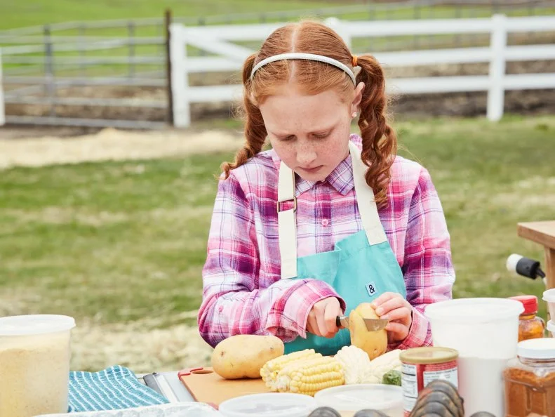 Contestant Raegan Frash preparing her Round 2 dish, New England Clam Bake with Smoked Sausage, as seen on Kids BBQ Championship, Season 2.