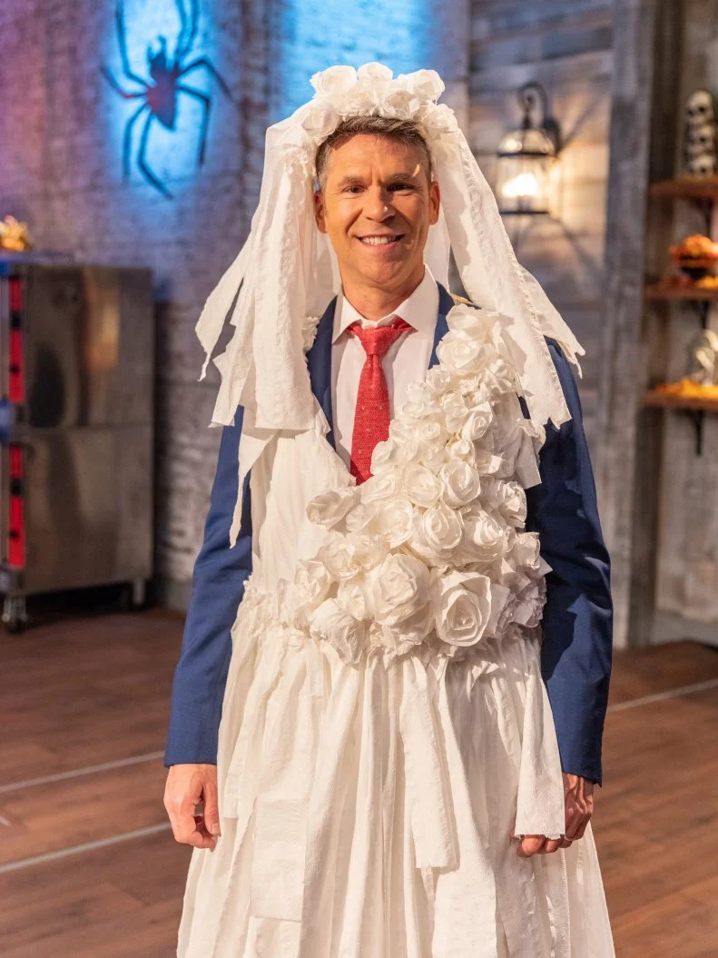Host John Henson poses for a photo in his wedding dress costume, as seen on Food Network's Halloween Baking Championship, Season 4.