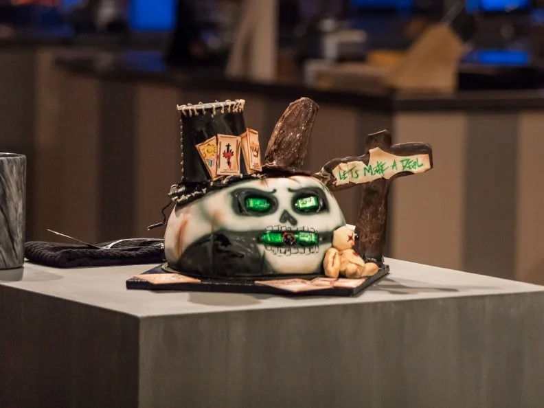 Contestant Jasmin Bell next to her completed dish, Chocolate Cake with Nutmeg and White Chocolate Filling and Chocolate Ganache, in the main heat, as seen on Food Network's Halloween Baking Championship, Season 3.