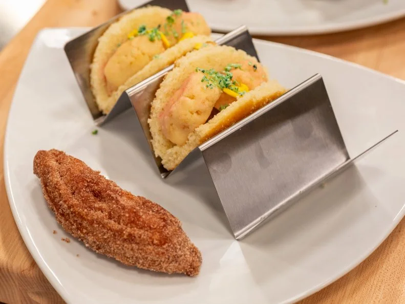 Contestant Paige Goehner's completed dish from the main bake, Vanilla cake taco shell with vanilla cake shrimp, coconut lettuce, and fondant cheese with a cinnamon sugar churro, as seen on Kids Baking Championship, Season 6.