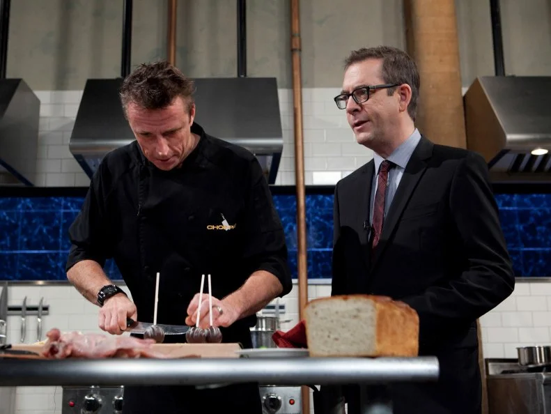 Chopped: After Hours host Ted Allen talks with chef Marc Murphy while he works on his entree that must include: Chocolate cake pops, white chocolate cocoa mix, quail and Serrano peppers, as seen on Food Network's Chopped: After Hours.