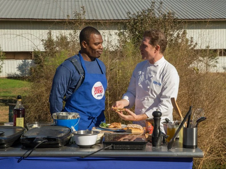 Host Bobby Flay talks with contestant Lance Greene after a cooking challenge on Cherry Grove Farm as seen on Food Networkâ  s Worst Cooksin America, Season 5.