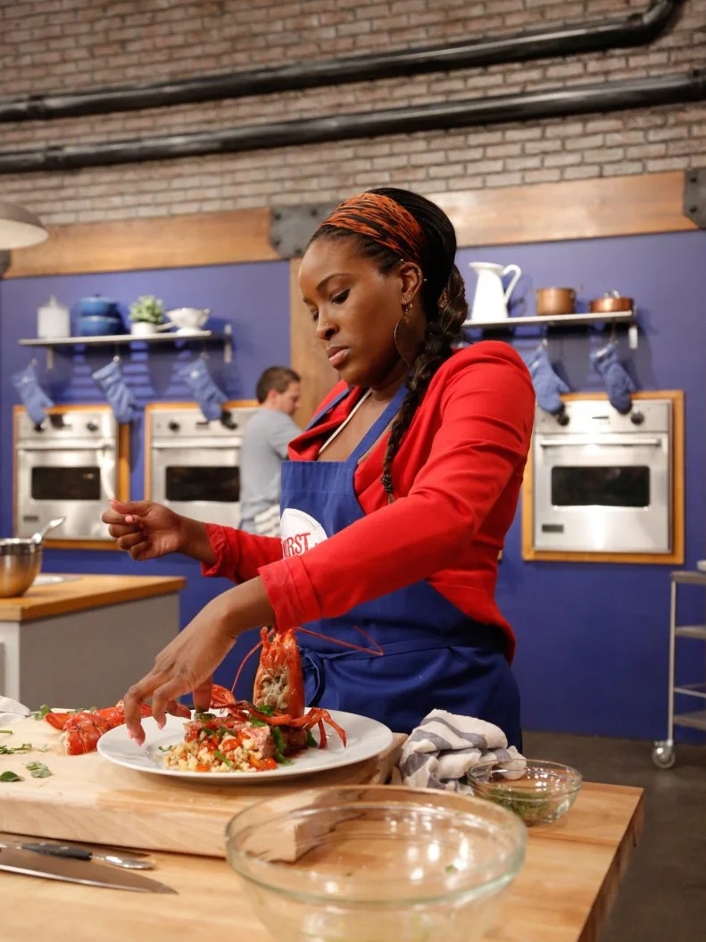 Blue Team member Stephanie St. Aubin puts the finishing touches on her dish for the Surf and Turf Challenge. Each team must replicate a steak and lobster dinner from scratch, demonstrated to them by their team leader; Grilled Ribeye with Fra Diavolo Lobster Relish by Chef Bobby Flay for the Blue Team, and Dry Rubbed Rib Eye with Chili Lobster by Chef Anne Burrell for her Red Team, as seen on Food Network's Worst Cooks in America, Season 5.