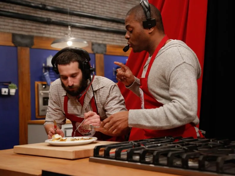 The Red Team, Mike Glazer and Jamie Thomas, taste and try to accurately describe the appearance, ingredients and flavors of their Halibut with Endive and Gremolata,, during the Remote Control Skill Drill. They have to direct Red Team Leader Chef Anne Burrell via headset to make the same dish they are seeing for the first time, as seen on Food Network's Worst Cooks in America, Season 5.