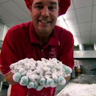 A man making Texas Trash is holding the candy coated confection out in his hands to see.