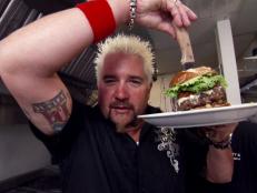 Guy poses with a burger as big as his head. This is a burger from Pawley's Front Porch Restaurant in Columbia, SC.