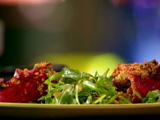 A close up of stuffed piquillo peppers with chorizo and manchego with an arugula salad in between.