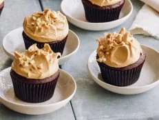Chocolate cupcakes and peanut butter icing with chopped peanuts on top.