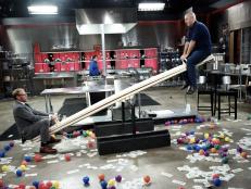 Hosts Alton Brown and Simon Majumdar on the sabotage element, "See Saw Prep and Cook", as seen on Food Network's Cutthroat Kitchen, Season 7.