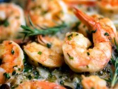 Close image of jumbo shrimp being sauteed in a pan with oregano, chive, rosemary, garlic and paprica creating Shrimp Scampi