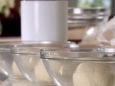 Three oiled glass bowls with equal sized balls of pizza dough in each. These balls of dough will rest for several more hours before they will be ready to use to make pizza.