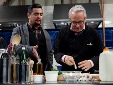 Chopped: After Hours host Aaron Sanchez talks to chef Geoffrey Zakarian while he is working on his entree that must include: deep dish pizza dough, rabbit escabeche, swiss chard and pineapple cheese spread, as seen on Food Network's Chopped: After Hours.