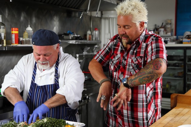 Guy Fieri is in the kitchen with chef/owner Tony Zarlenga of Café Brazil in Denver, CO where chef Tony is hand mixing the mixture for his Bolhinos de Batate Doce as seen on Food Network's Diners, Drive-Ins and Dives episode 2303.